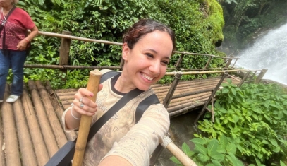 A student in front of a waterfall during a research trip.