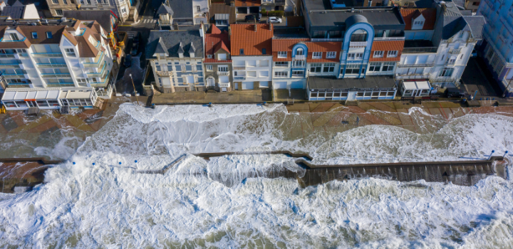 Waves crashing onto buildings on a coastline