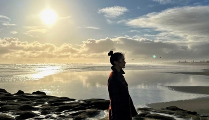 A student on a beach with a sunrise in the background