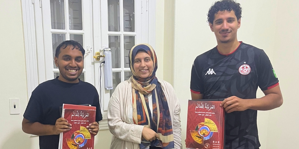 Taher and his fellow undergraduate researcher, Yanis Zaim, posing with their Arabic language instructor at al-Diwan Center Maadi in Egypt, along with their study materials.
