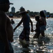 People walk through Lake Michigan at Montrose Beach in Uptown as Chicago hit the daily record high at 100 degrees on Aug. 24, 2023.