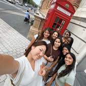 A group of students take a selfie in front of a red phone booth in England. 