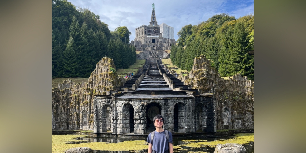 Xiong in front of a statue of Hercules atop a fountain in Germany.