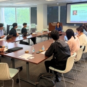 Students from The University of Tokyo gathered around a table listening to Buffett Institute staffer Hiroko give a lecture
