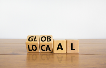 Wooden blocks with letters on them spell out the words "Global" and "Local."
