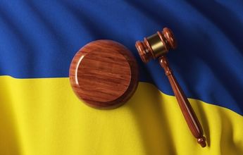 A wooden gavel on top of a Ukrainian flag. 