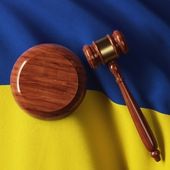 Wooden legal mallet lying on top of the Ukrainian flag.
