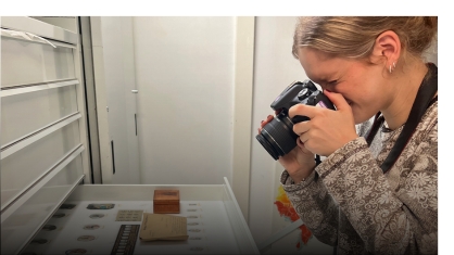 A student taking a photo of artifacts in a drawer