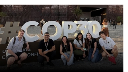 Students standing in front of a sign at the COP30 conference