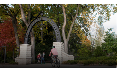 Students biking in the summer through Weber arch.